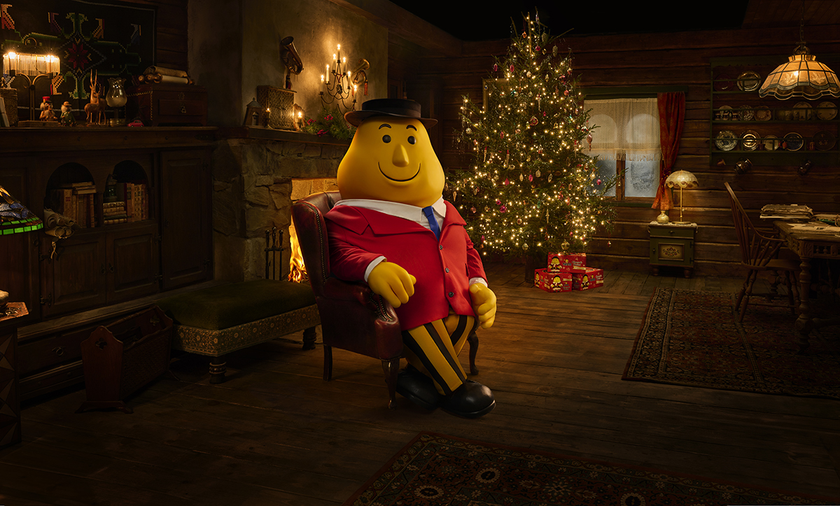 Mr Tayto sitting at a christmas tree in a cosy cabin